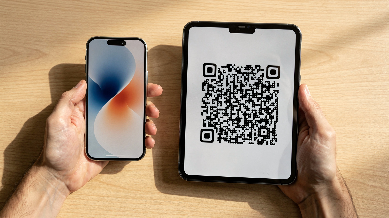 Close-up of human hands holding a smartphone, with a second device displaying a QR code, showing the digital installation of an eSIM.
