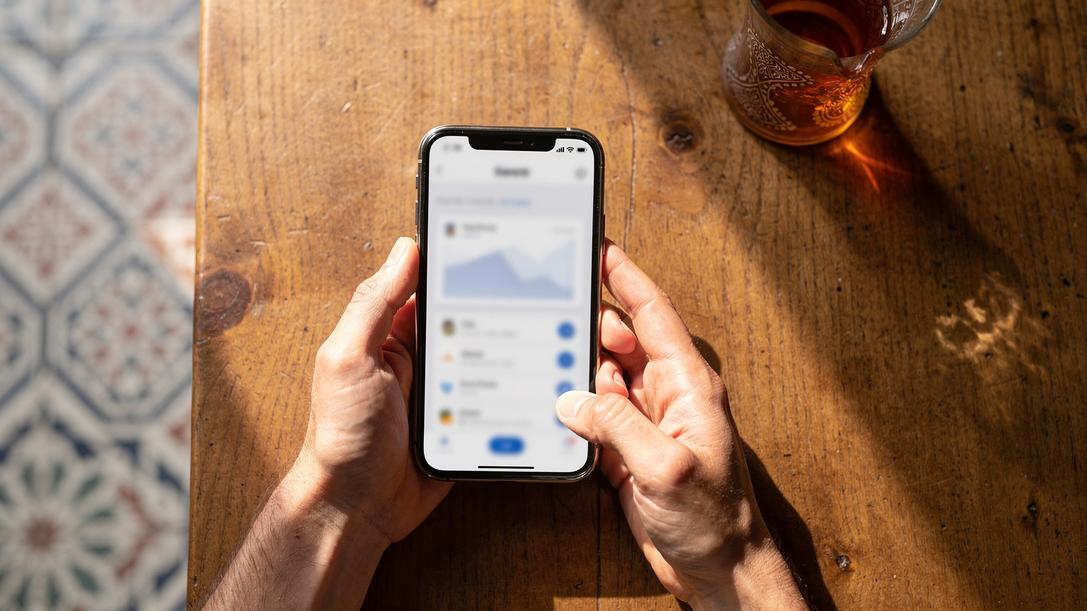 A traveler carefully reviews eSIM data plans on their smartphone, comparing costs and data allowances against a backdrop of traditional Moroccan patterns, emphasizing smart financial choices.